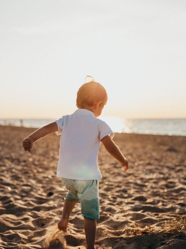 menino de costas na praia